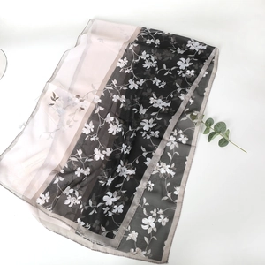 Detailed view of pink and black floral chiffon scarf with soft translucent fabric texture