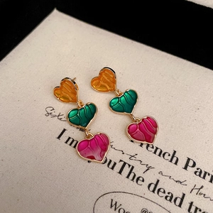 Macro detail of three-tier heart earrings with colorful enamel and gold metal frames