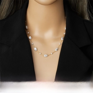 Detail of elegant gold chain necklace with varying white pearls on black suit lapel