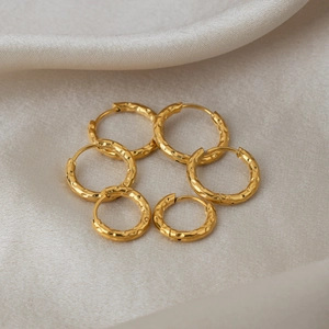 Minimalist 18K gold plated hammered texture hoop earrings on beige silk fabric