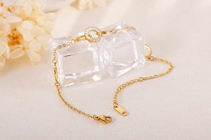 Detail of gold chain bracelet with zircon-encrusted O-ring on clear ice cubes