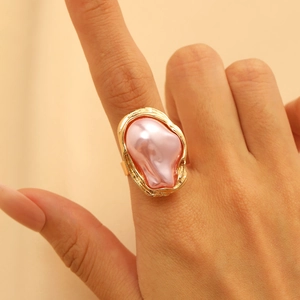 Nahaufnahme eines goldenen unregelmäßigen Rings mit einer großen rosa Barockperle