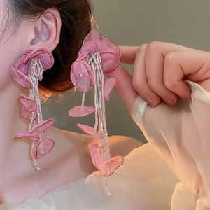 Detail of dusty pink fabric flower earrings with long beaded tassels on model
