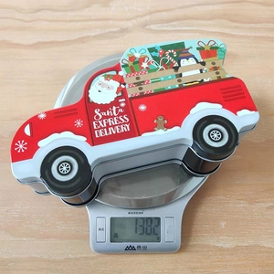 Close-up of Christmas tin candy box in truck shape on a scale showing 138.2g weight
