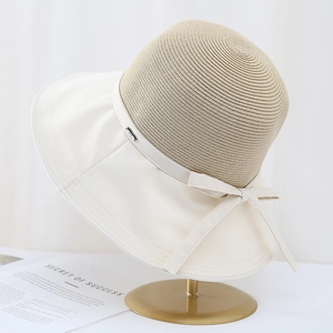 Detail of mixed-media sun hat showing fine straw weave and white fabric brim with bow