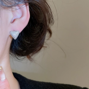 Détail macro des boucles d'oreilles triangles scintillantes avec pavé de cristaux