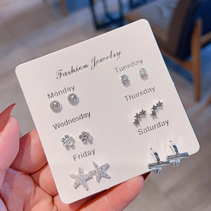 Close-up of 6 pairs of silver earrings with heart, star and cross shapes on a display card