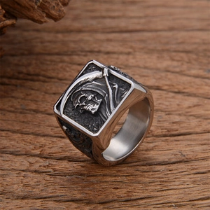 Close-up of gothic grim reaper skull ring with vintage silver finish on dark wood surface