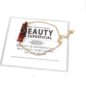 Detail of reddish-brown natural stone bracelet with gold chain and lobster clasp