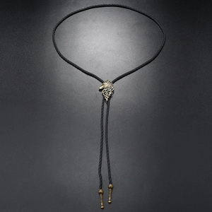 Detailed view of wolf head bolo tie with antique bronze metal and black leather cord