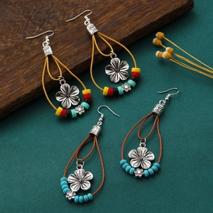 Detail of bohemian drop earrings with braided cord and silver floral charms