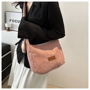 Pink corduroy tote bag with side pendant shown on model in minimalist setting