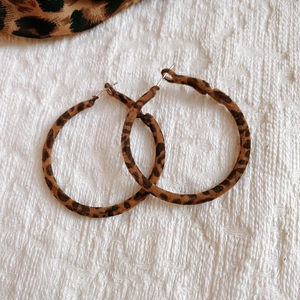 Gros plan sur des boucles d'oreilles créoles léopard avec texture pelucheuse sur fond blanc
