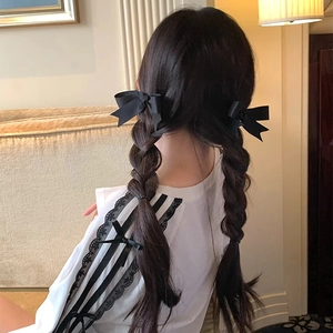 Elegant black satin bow hair clip worn on double braids for a French vintage style