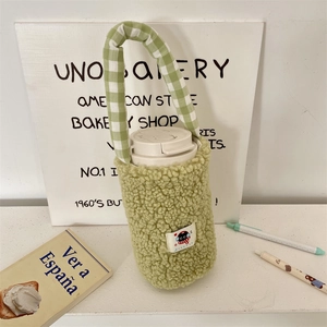 Primer plano de bolsa de peluche verde para botella con parche de gato y asa de cuadros