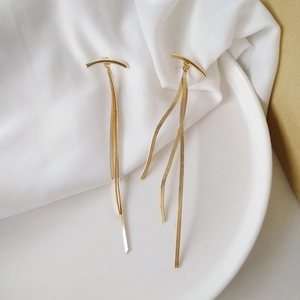 Elegant gold long tassel drop earrings with sleek metal chain fringe on white ceramic tray