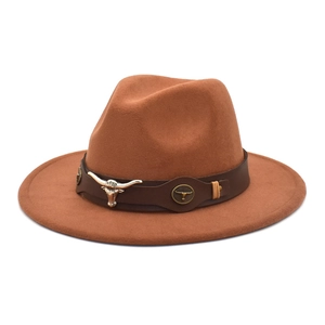 Detail of a brown felt fedora featuring a metallic bull head ornament on a leather band