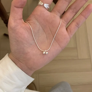 Detailed view of silver necklace with double ball pendant and engraved wide open ring