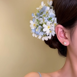 Close-up of elegant light blue and white flower hair clip styled on a low bun hair