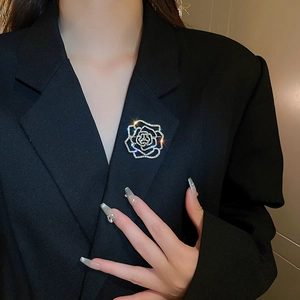 Exquisite hollow camellia brooch with sparkling rhinestones pinned on a black suit blazer