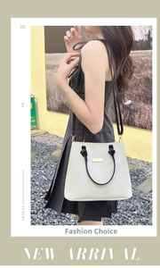 Detail view of cream-colored leather tote bag with gold buckle and black shoulder strap