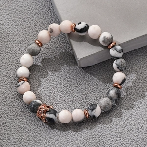 8mm Weiß-Türkis Perlenarmband mit roségoldenem Kronenanhänger auf grauem Steinhintergrund