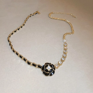 Detailed macro view of woven leather chain necklace with camellia flower and pearl pendant