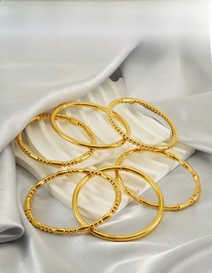 Dettaglio di bracciali in acciaio inossidabile dorato con texture bambù e perline