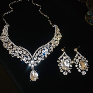Macro shot of silver teardrop necklace and earrings set with clear crystals on velvet