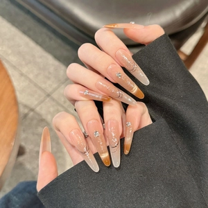 Long almond press-on nails with amber gradient, cat-eye effect, sequins, and rhinestones