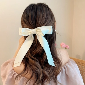 Large ivory satin bow hair clip with ribbons shown on long wavy hair back view