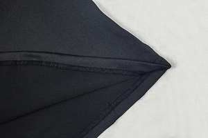 Macro shot of fine black knitted fabric texture and durable double-stitch hem on the dress