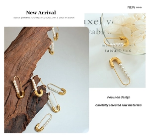 Detail of paperclip style 18K gold plated earrings with white pearls on a wood block