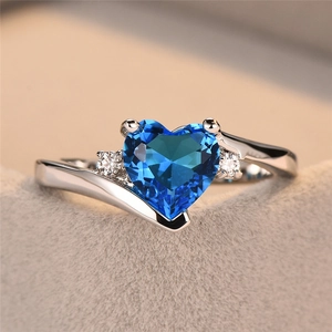 Macro shot of heart-shaped blue zircon ring with silver band on velvet stand