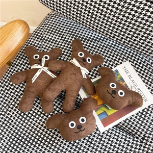 Cute brown plush teddy bear dolls with mini bear ribbon sitting on a houndstooth chair