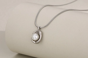 Detail of silver snake chain necklace with irregular pendant and embedded pearl