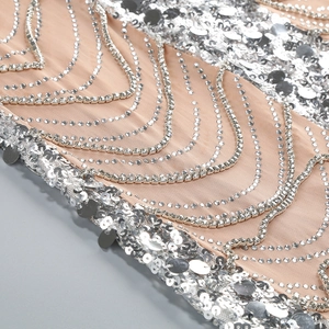 Macro detail of silver sequins and rhinestone chain pattern on mesh evening gown
