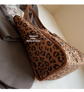 Detailed close-up of a leopard print tote bag with brown leather trim in a stylish setting