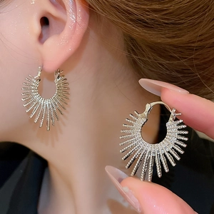 Macro view of silver geometric sunburst earrings showing polished texture and metal detail
