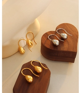 Macro detail of polished teardrop dangle earrings in gold and silver finishes