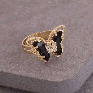 Macro detail of a golden butterfly ring featuring black gemstones and white rhinestones