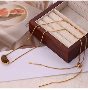 Gros plan du collier doré avec pendentif oeil de tigre et fermoir à bille ajustable