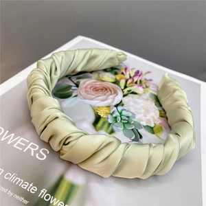 Detail of light green pleated silk headband with elegant satin luster on vintage book