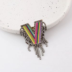 Close-up of V-shaped brooch with rainbow stripes, rhinestones and fringe tassels