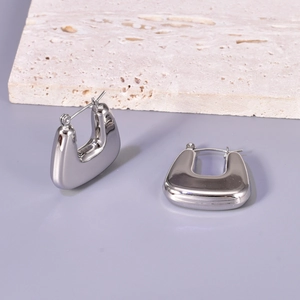 Close-up of polished silver stainless steel U-shaped hoop earrings on a textured stone