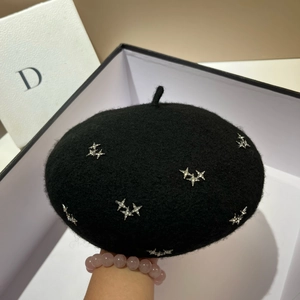 Close-up of black wool beret featuring shiny silver star accents and premium texture