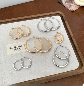 Close-up of minimalist gold and silver hoop earrings in multiple sizes on display