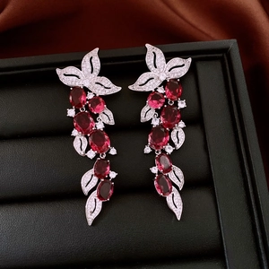 Detailed macro of vintage leaf earrings featuring silver base and red oval gemstones