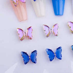 Macro shot of 3D crystal butterfly nail charms with purple facets and gold metal edges