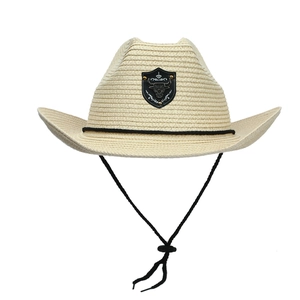 Detail of a beige straw cowboy hat with a bull head shield emblem and adjustable chin strap